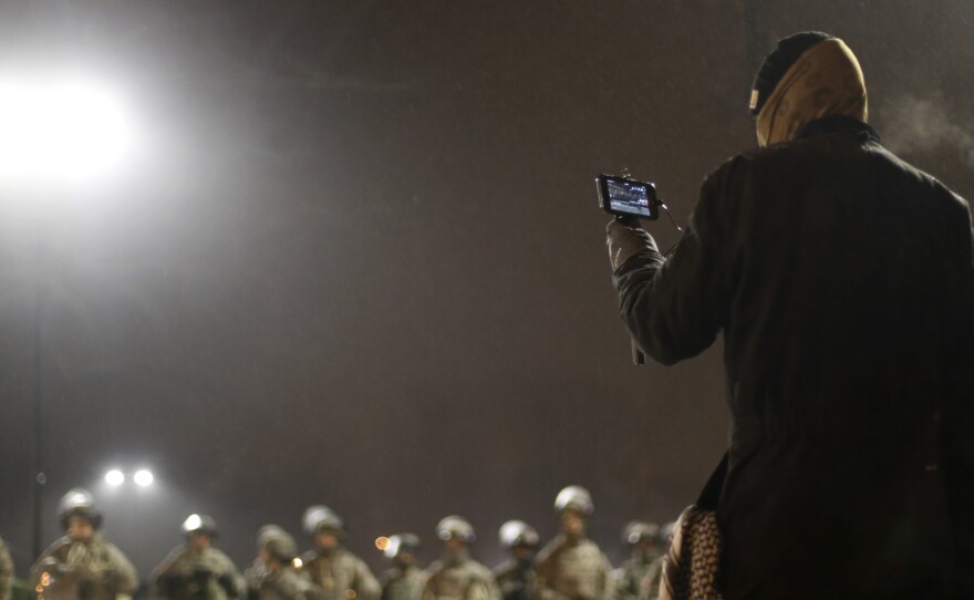 A protester films National Guard troops Nov. 26 in front of the Ferguson Police Department in Ferguson, Mo.