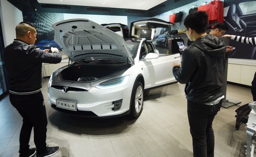 Customers look at Tesla cars at a showroom in Hangzhou in China's eastern Zhejiang province on April 4, 2018.