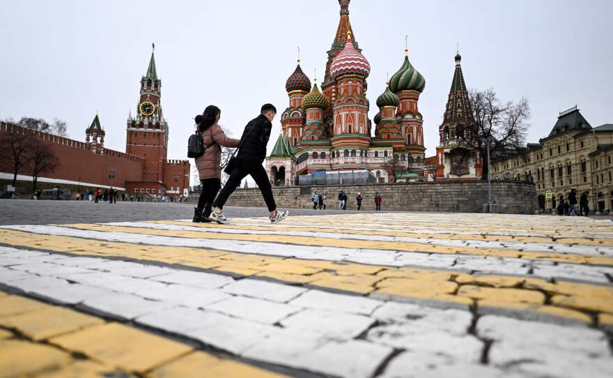 A couple walk in front of the Kremlin's Spasskaya Tower and St Basil's cathedral in downtown Moscow. While 80% of poll respondents say they support Russia's military, some have mixed feelings.