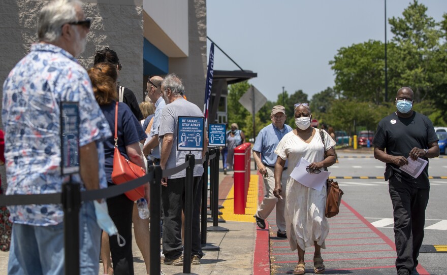 Voters (right) walk past a line of residents waiting to cast their ballot at the Gwinnett County Board of Voter Registrations and Elections in Lawrenceville, Ga., on May 18.