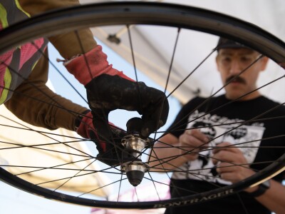 Fixing a broken spoke, Victor is helped by one of the volunteers of Bikes del Pueblo in San Diego.