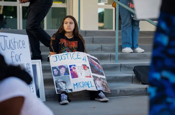 Protestors hold signs outside the John F. Tavaglione Executive Annex building in protest of jail deaths in Riverside County, on Oct. 31, 2023.