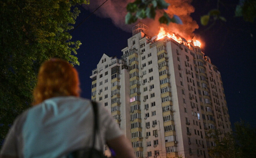 A woman looks at an apartment building burning after a Russian missile attack in Kyiv, Ukraine, Thursday, July 2, 2026. (AP Photo/Danylo Antoniuk)