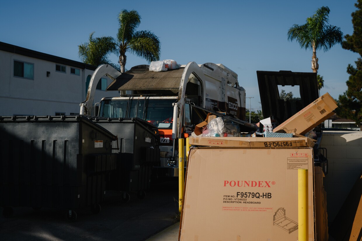 A garbage truck empties dumpsters filled with moving boxes and other debris outside the Hawaiian Gardens apartments in Imperial Beach on November 18, 2024.