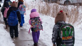 Students walk from the bus to their elementary school in St. Paul, Minn., on March 18. For many students, it was the first week back after nearly two months of online learning.