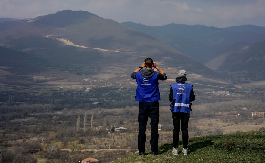 Members of the European Union Monitoring Mission peer through binoculars at the boundary line between Georgia and South Ossetia.