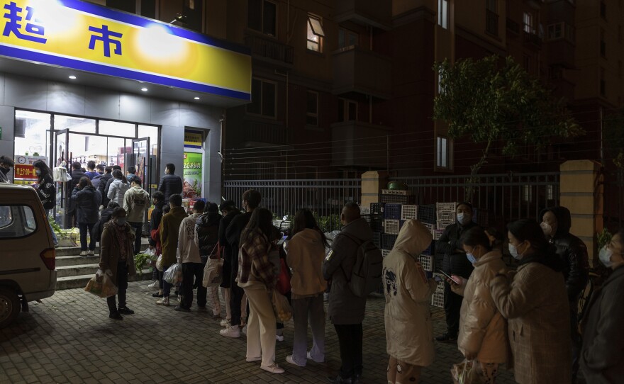 Residents line up outside a supermarket Sunday night to buy groceries in Shanghai, which is seeing lockdowns as part of China's strict anti-COVID strategy.