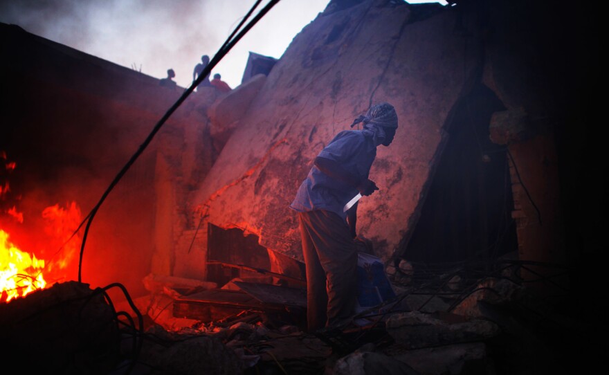 A man grips a knife as he looks for other looters to come out of a shop near downtown Port-au-Prince, Haiti.