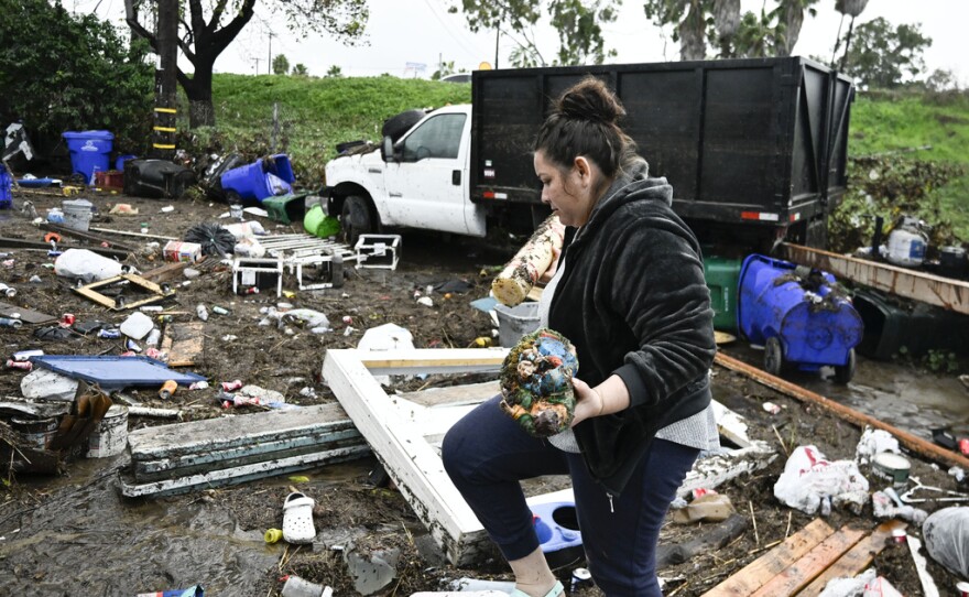 Marlene Sanchez-Barriento salavages items behind her home damaged by flooding, Tuesday, Jan. 23, 2024, in. Sanchez-Barriento's home was damaged when flood waters rushed though her home on Monday, Jan. 22. 