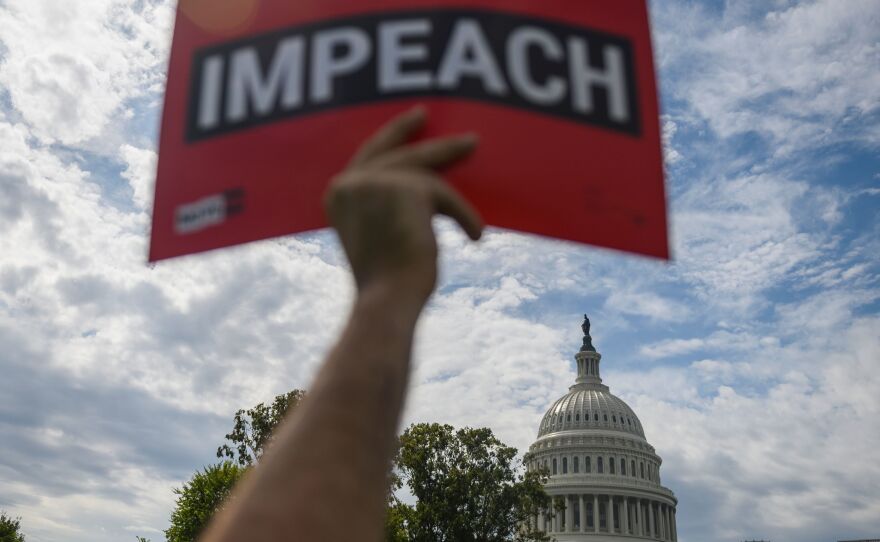 A protester holds up a sign in favor of impeachment outside the U.S. Capitol building on Thursday.